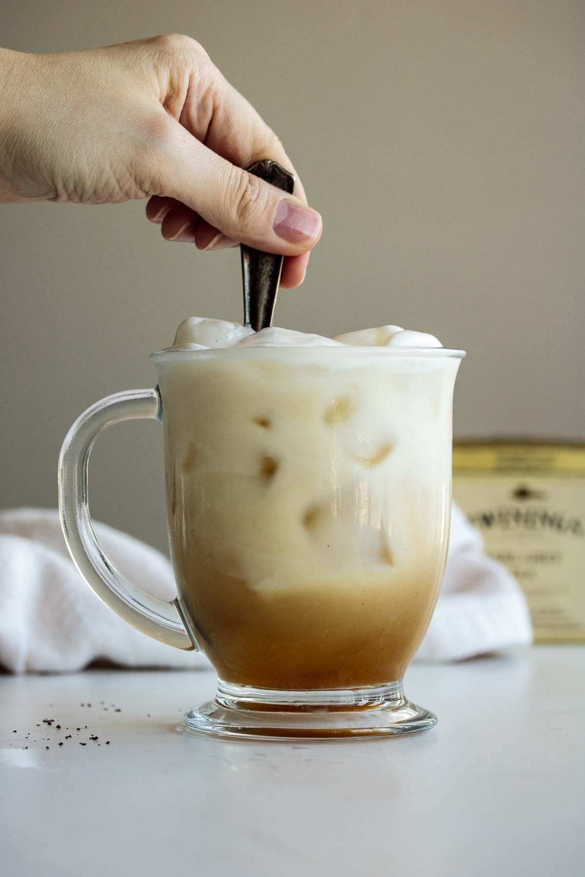 Hand mixing drink with a spoon.