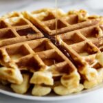 Maple syrup pouring over waffle disk.