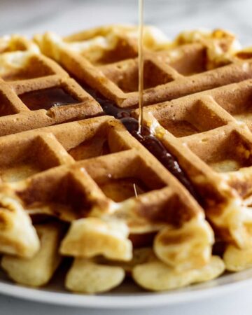 Maple syrup pouring over waffle disk.