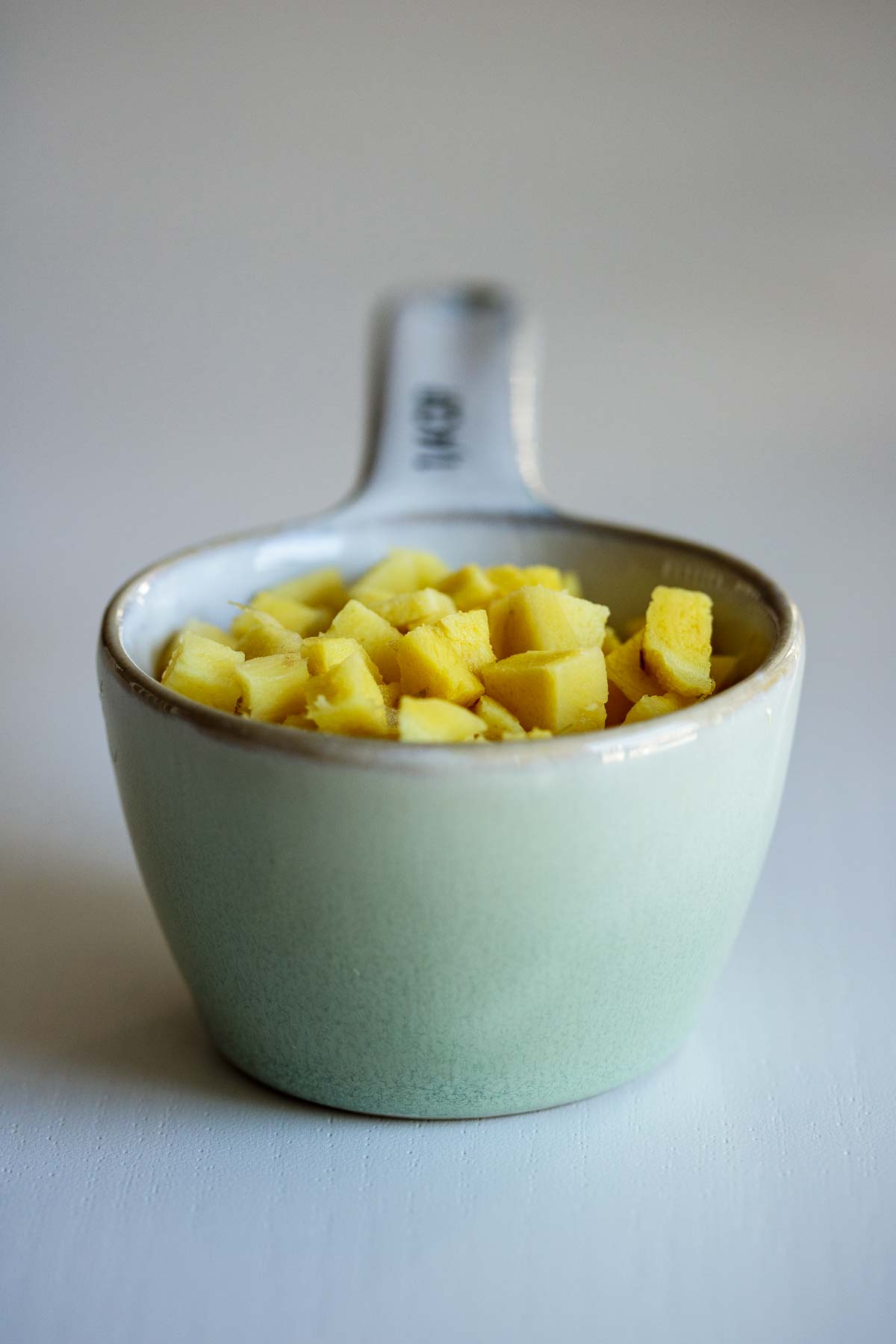 A quarter of a cup filled with cubed ginger.