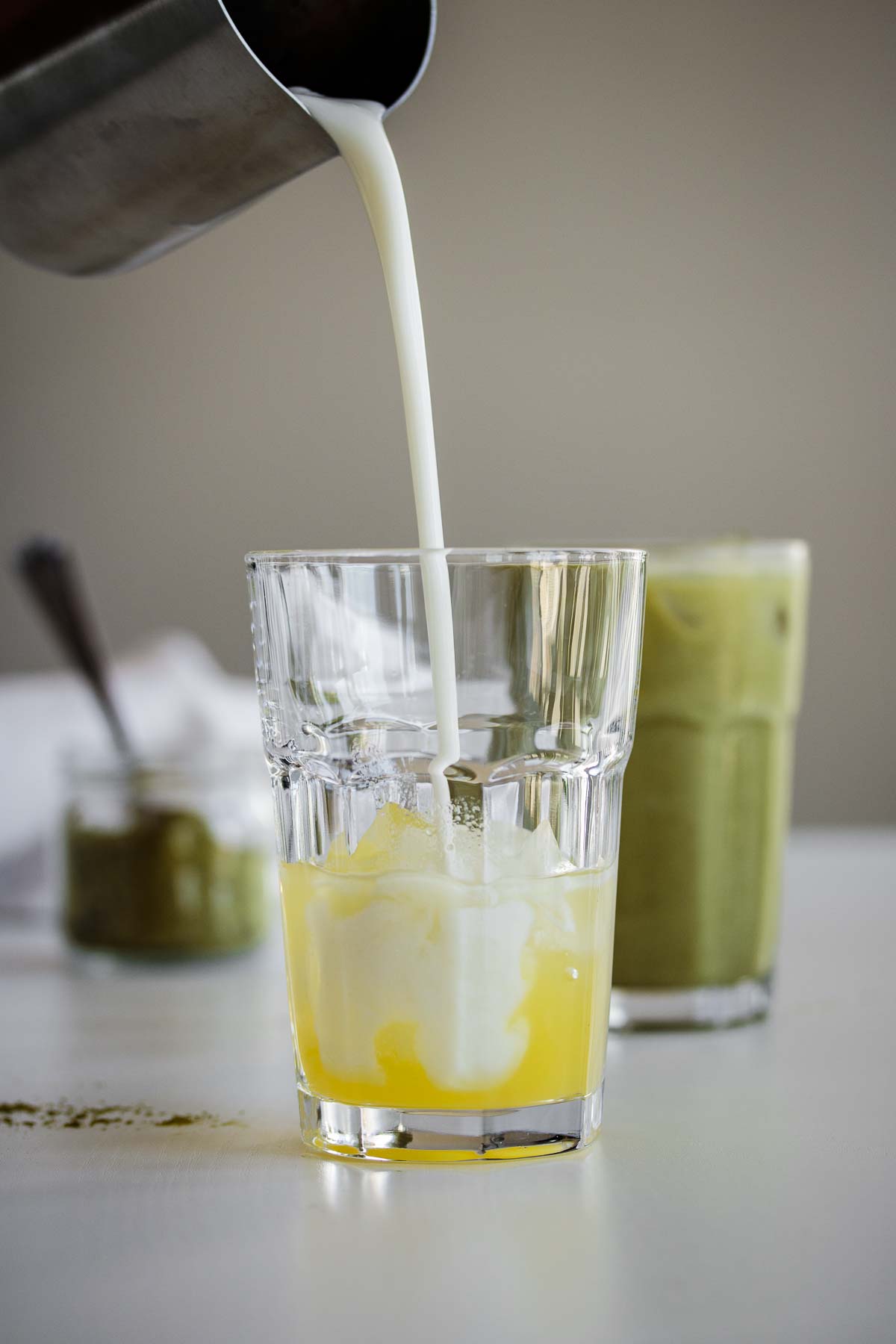 Coconut milk pouring over a glass with ice and syrup.