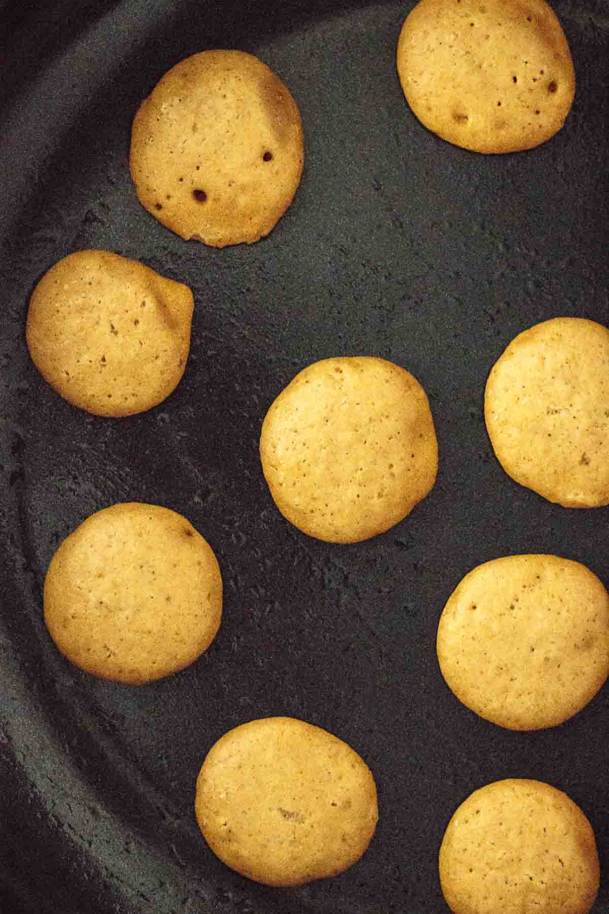 Mini pancakes in a pan ready to flip.
