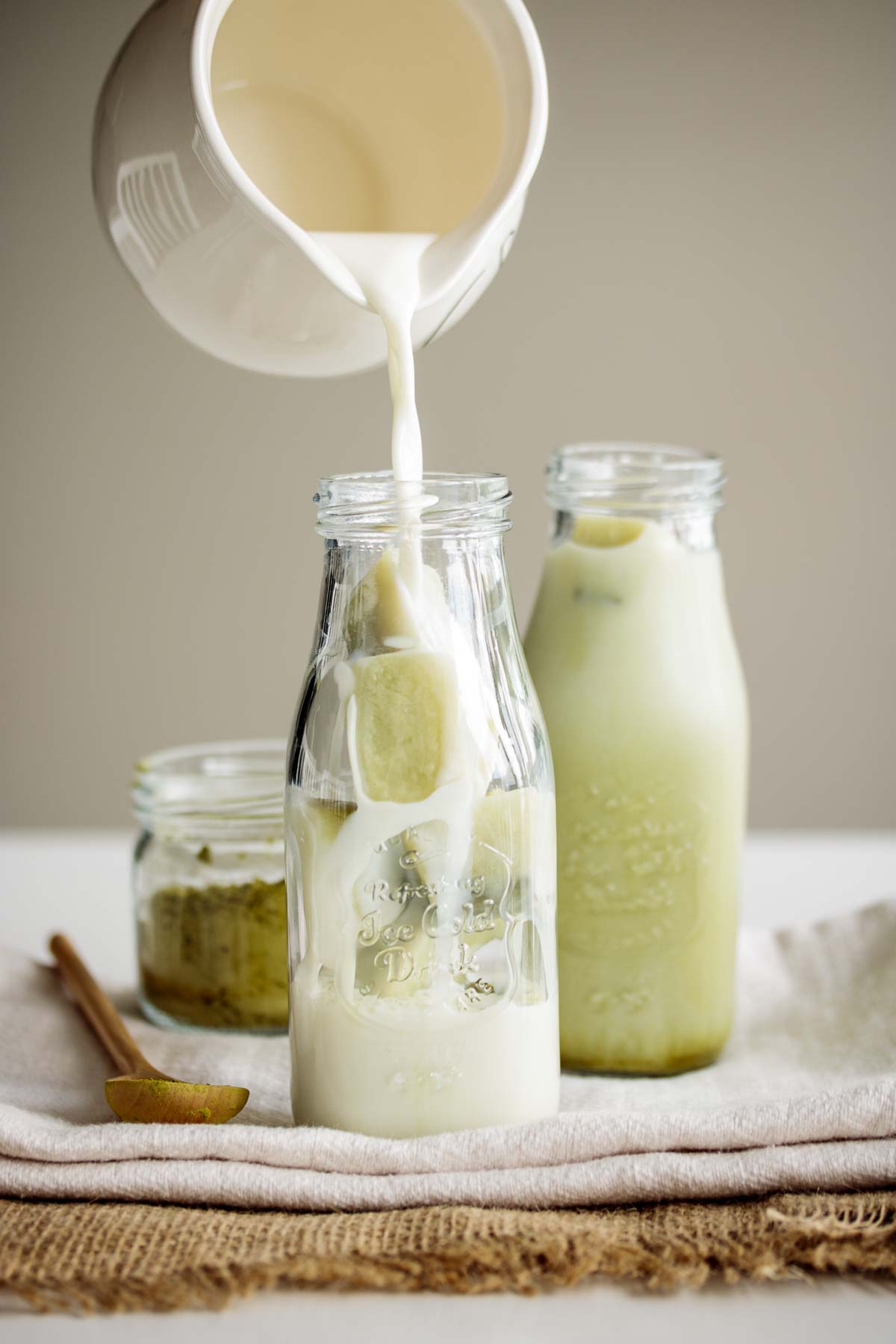 Milk pouring over matcha ice cubes.