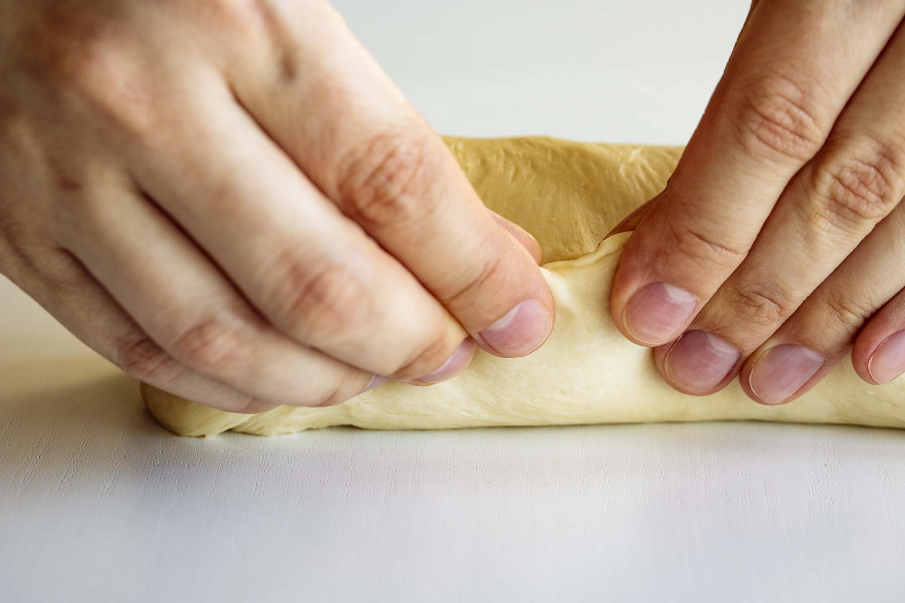 Hands pinching the dough close.