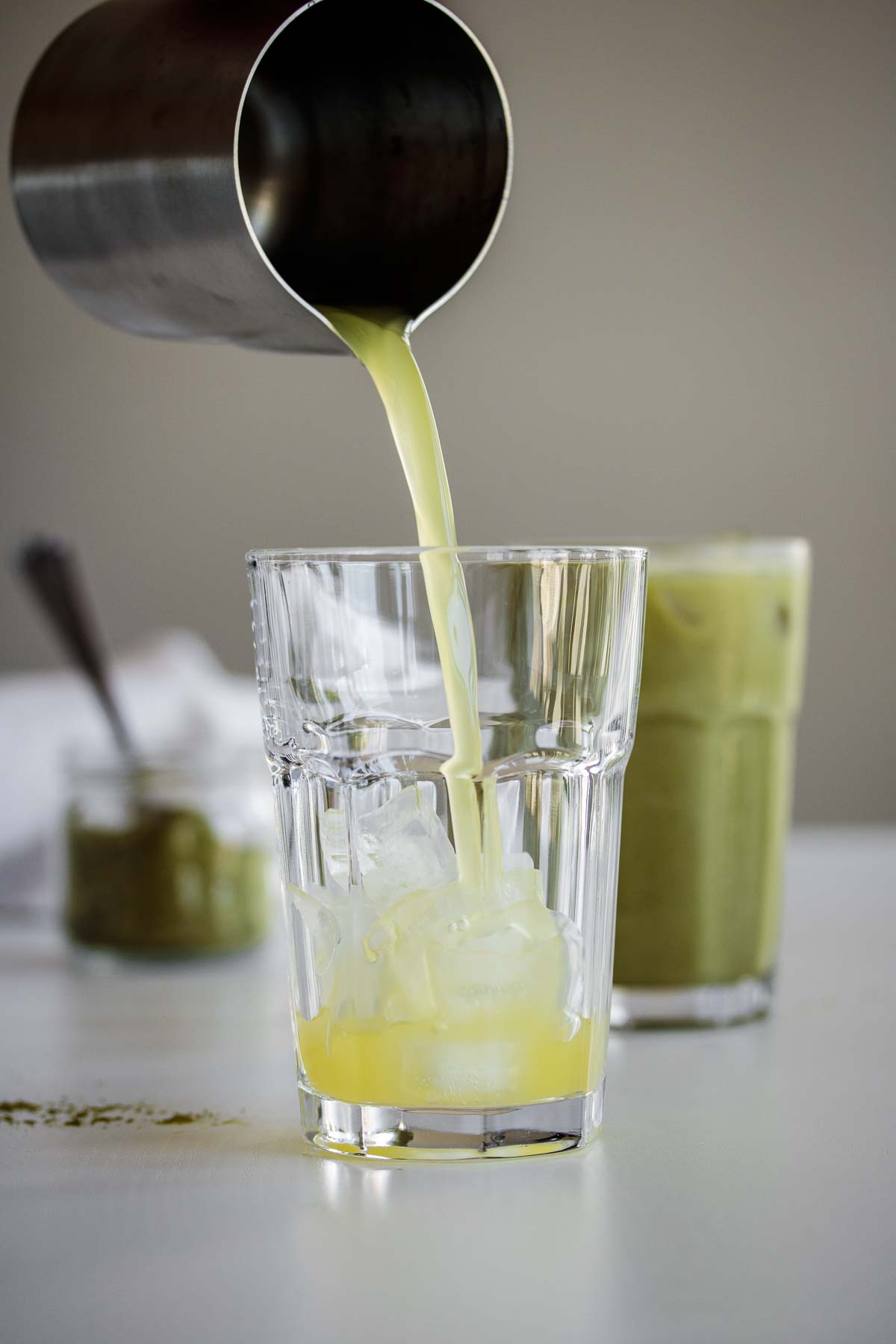 Syrup pouring into a glass cup with ice.