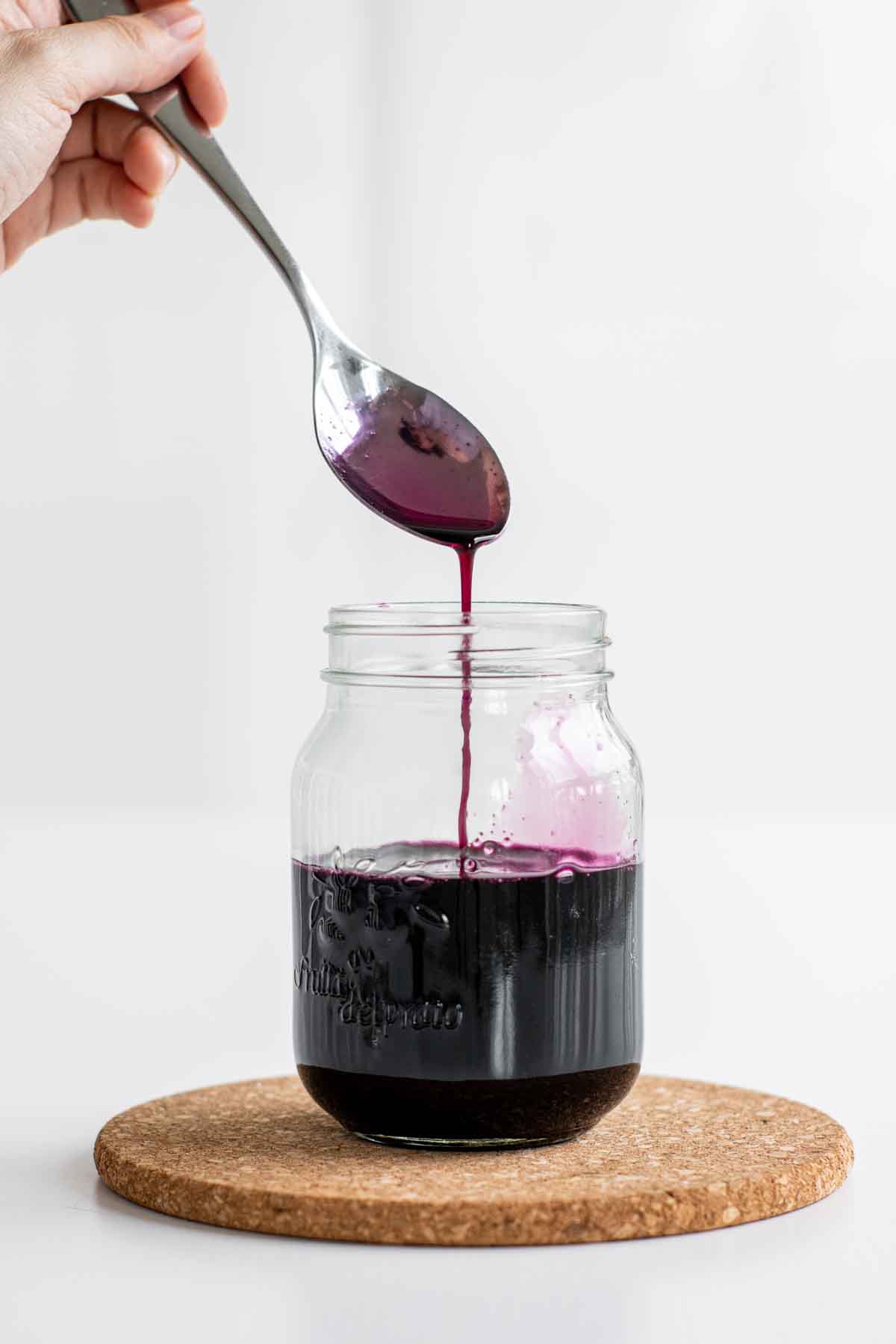 Blueberry syrup dripping from a spoon.