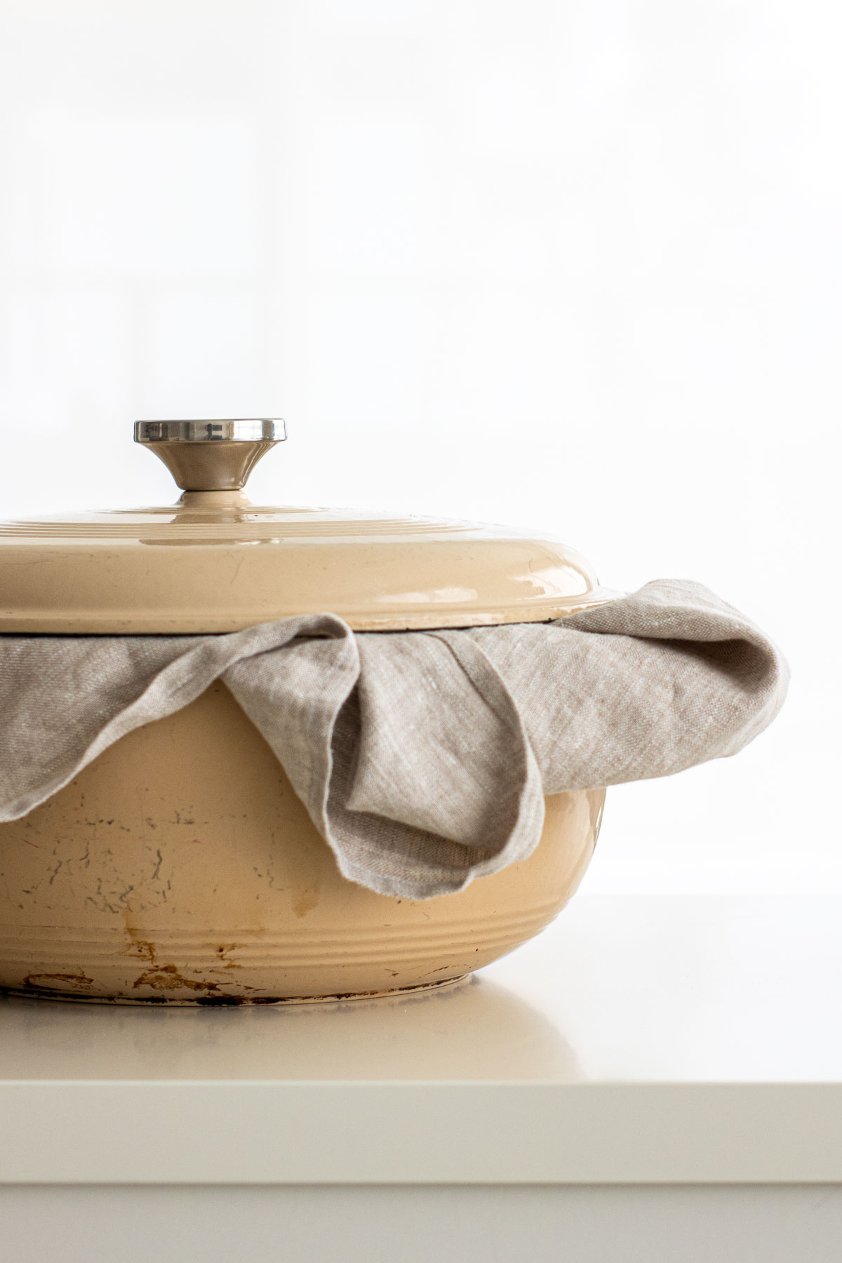 Dutch oven with lid sealed over linen towel, showing how to store sourdough bread.