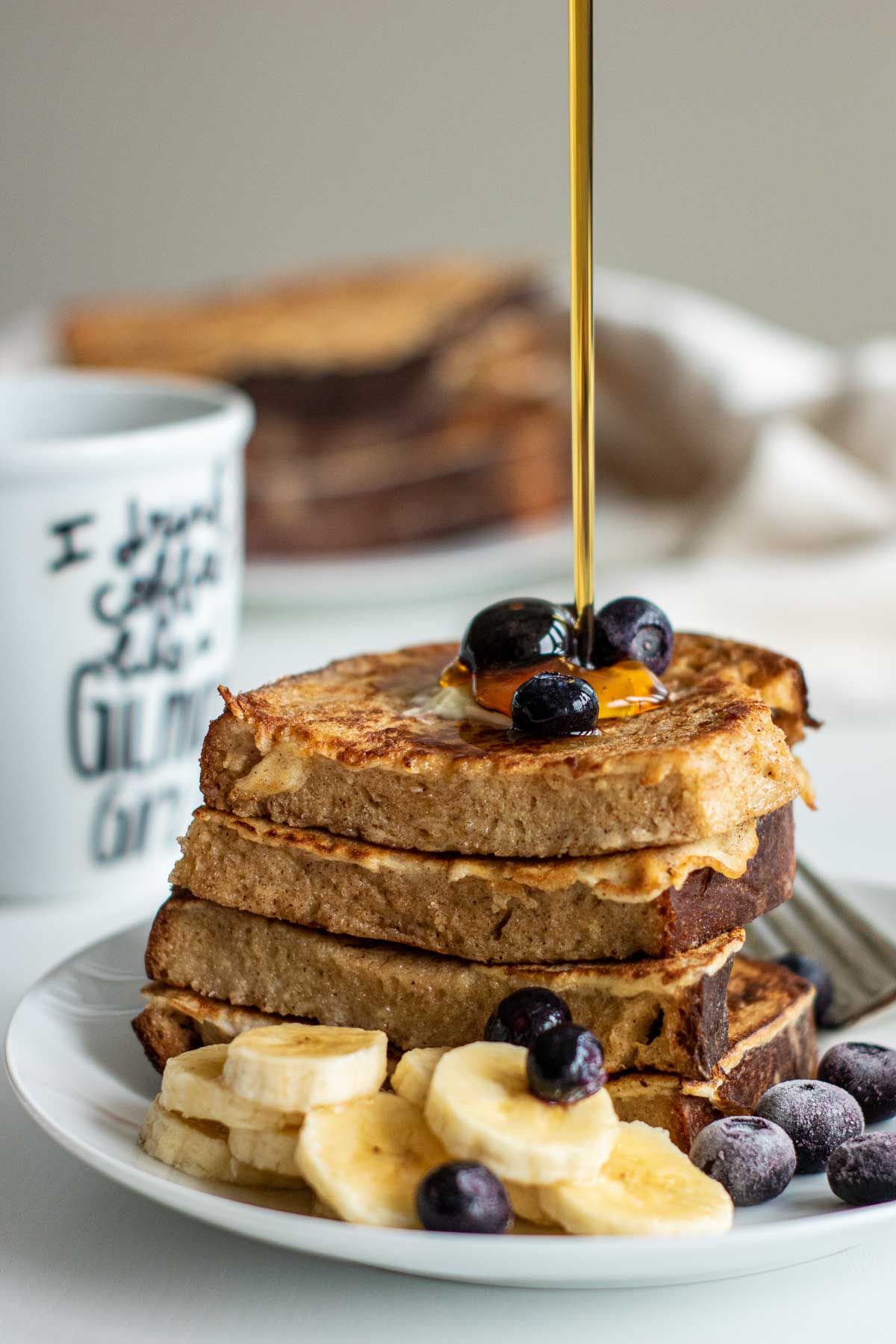 a stack of sourdough french toast, with honey drizzling over it