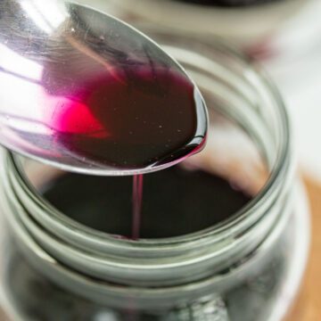 Blueberry simple syrup dripping from a spoon.