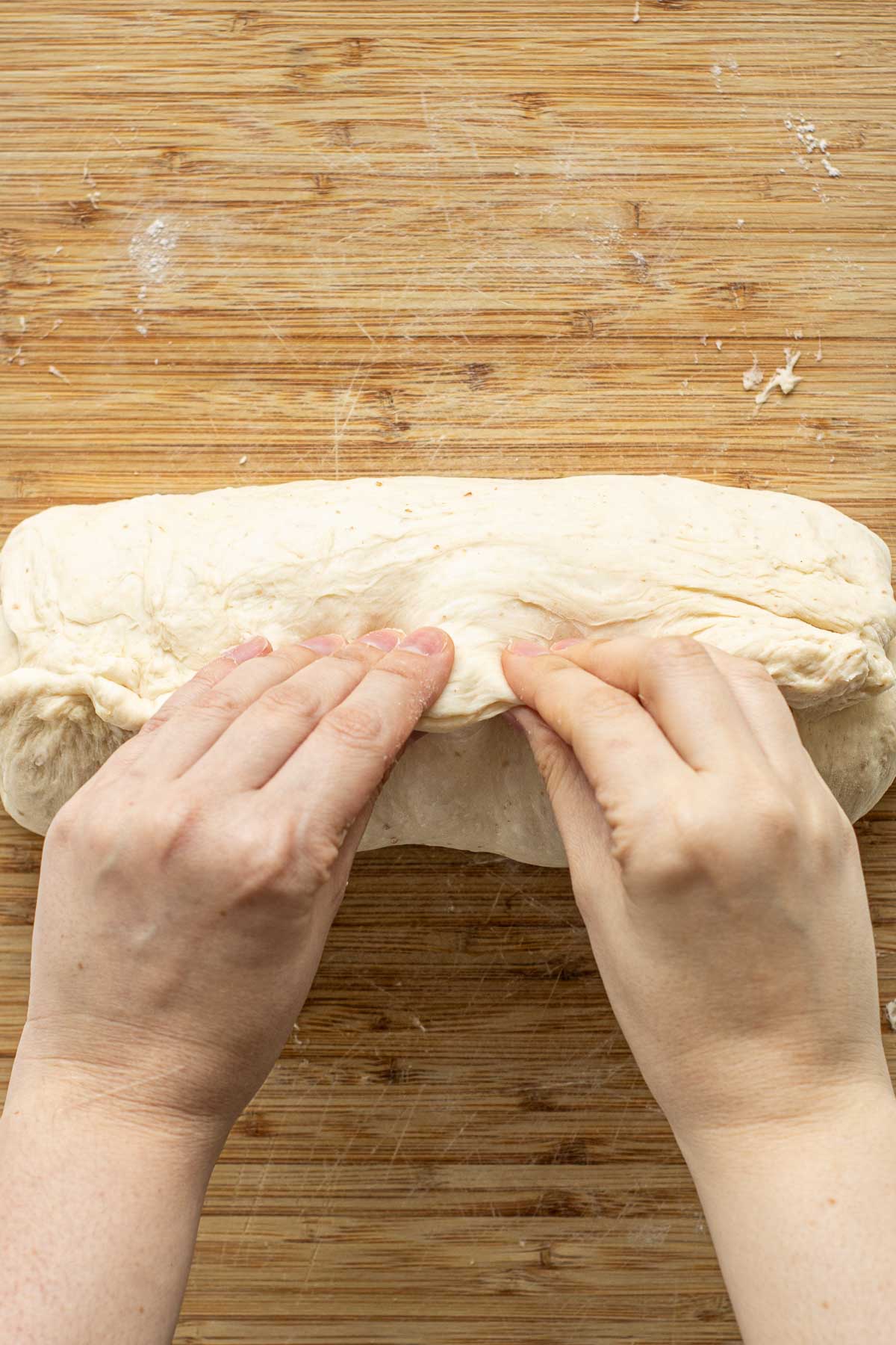 Hands pinching dough to close it.