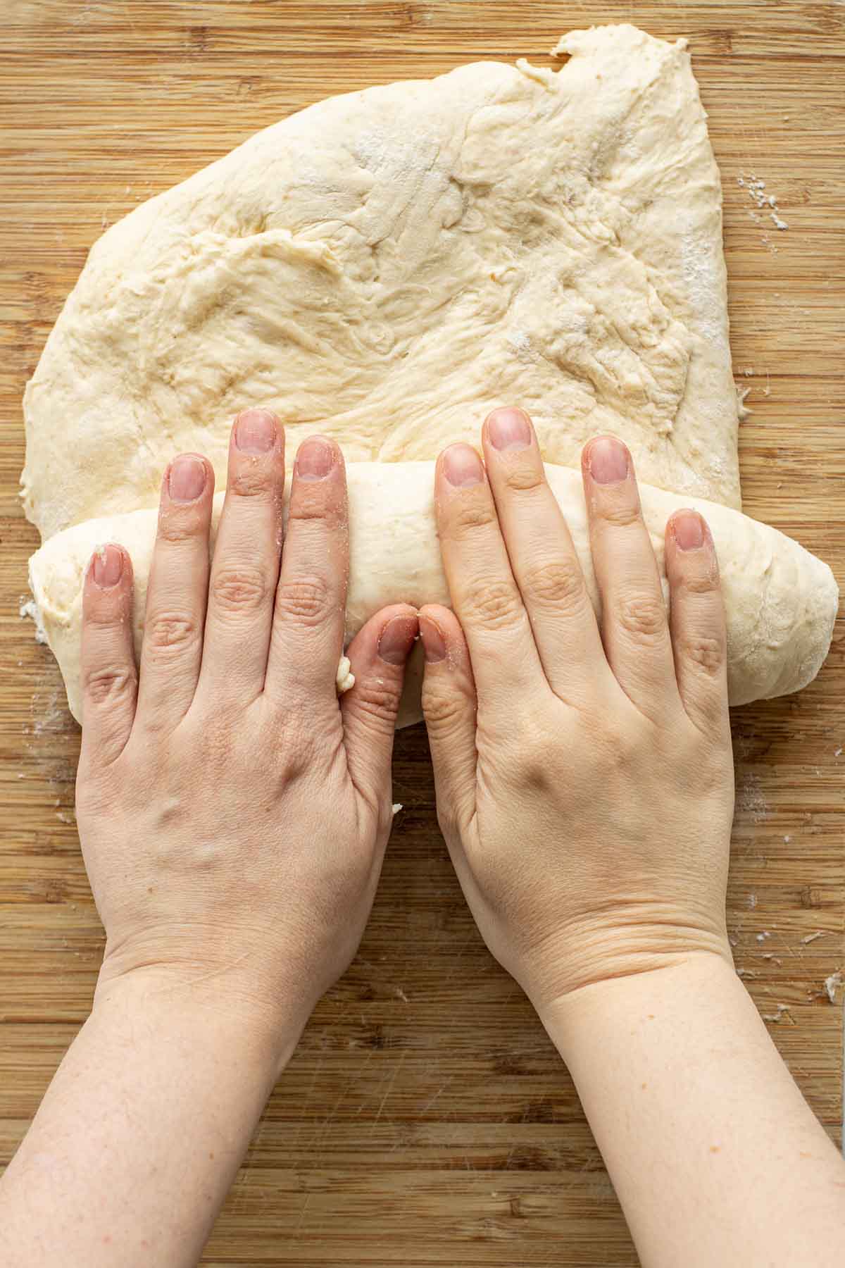 Rolling opened dough over itself.