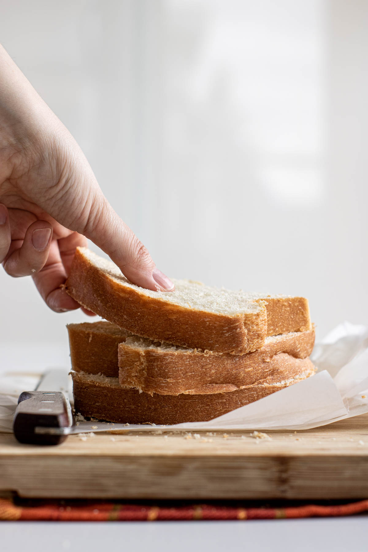 Hand grabbing a slice of sandwich bread.