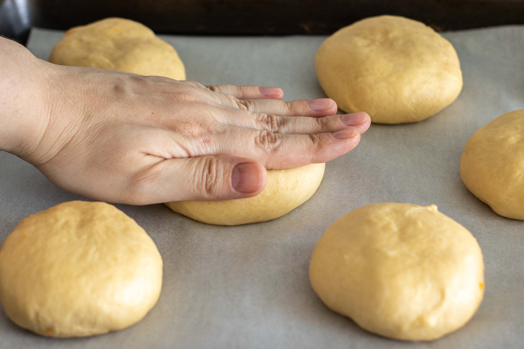 Hand pressing down the shaped dough.