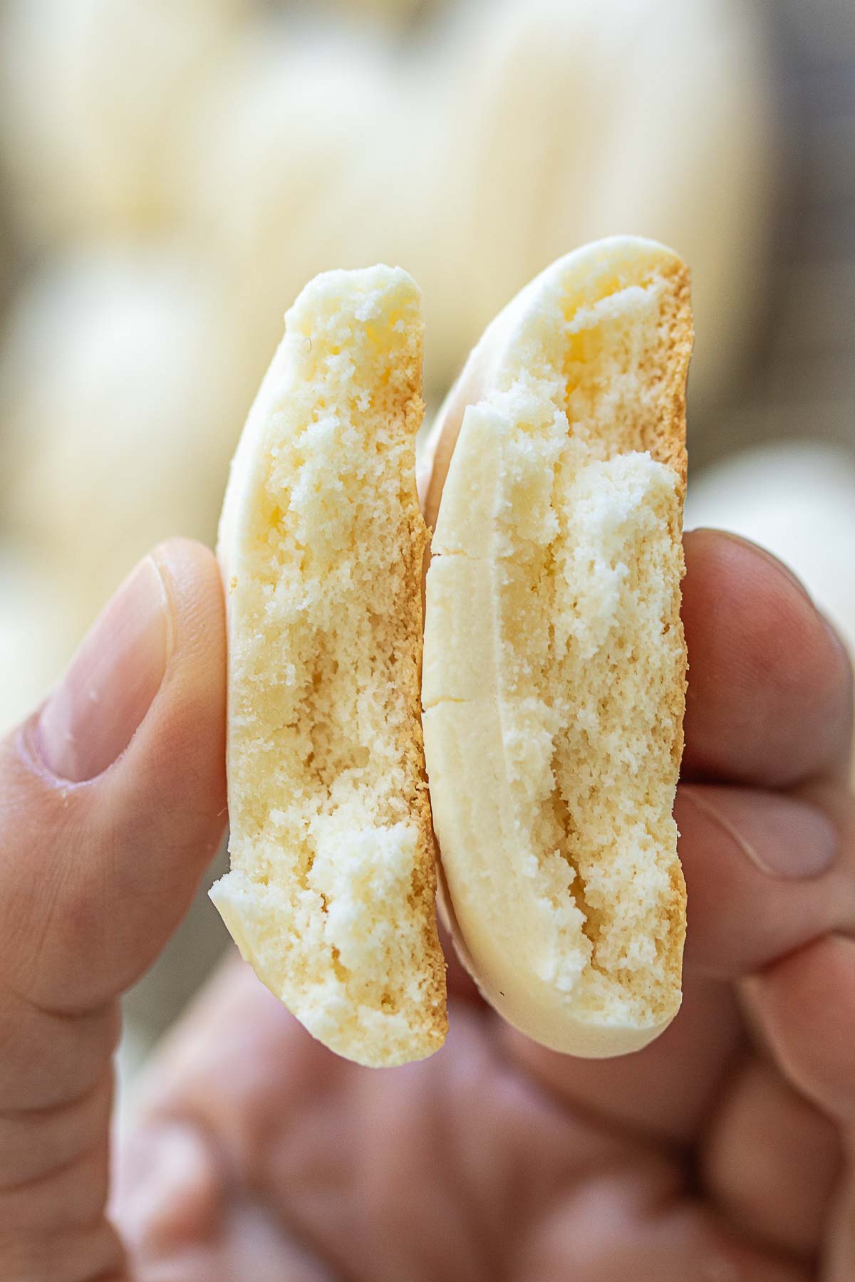 Hand holding a cornstarch cookie divided in half.