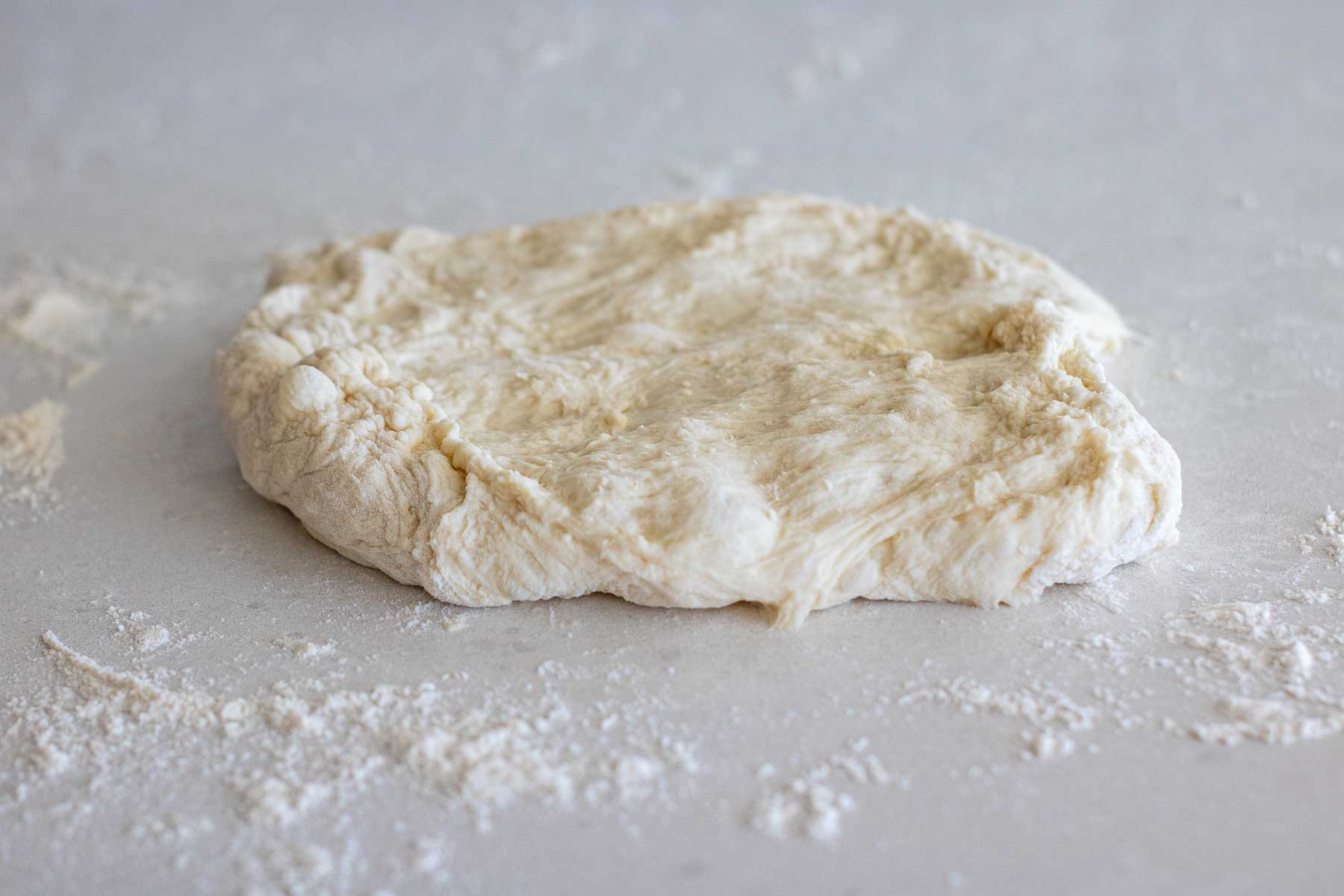 One part of the dough opened in a rectangle shape on a floured surface.