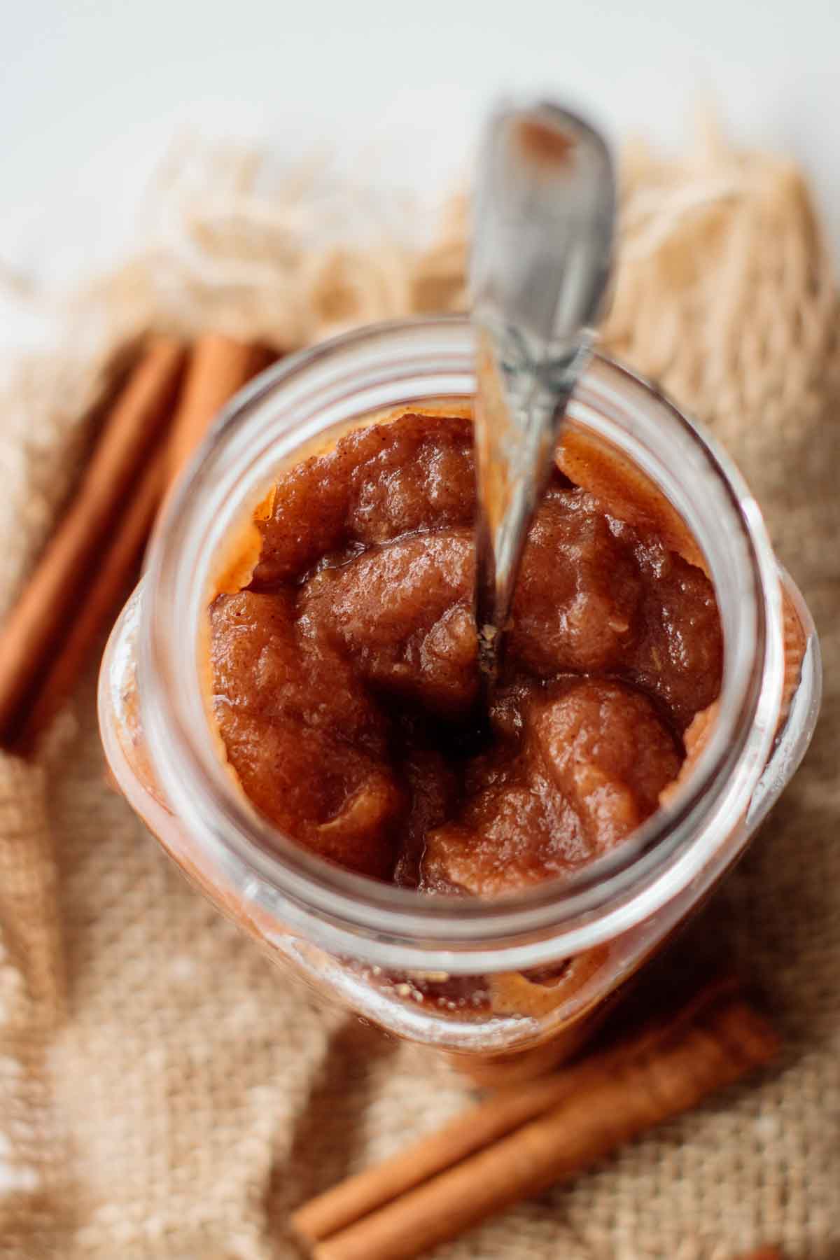 A jar of apple butter with a spoon inside.