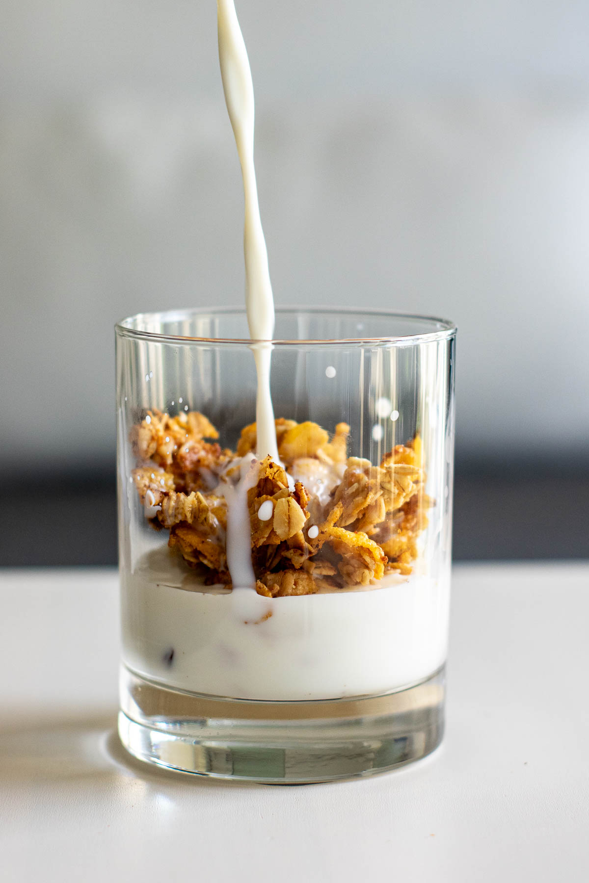 Milk spilling over granola in a glass.