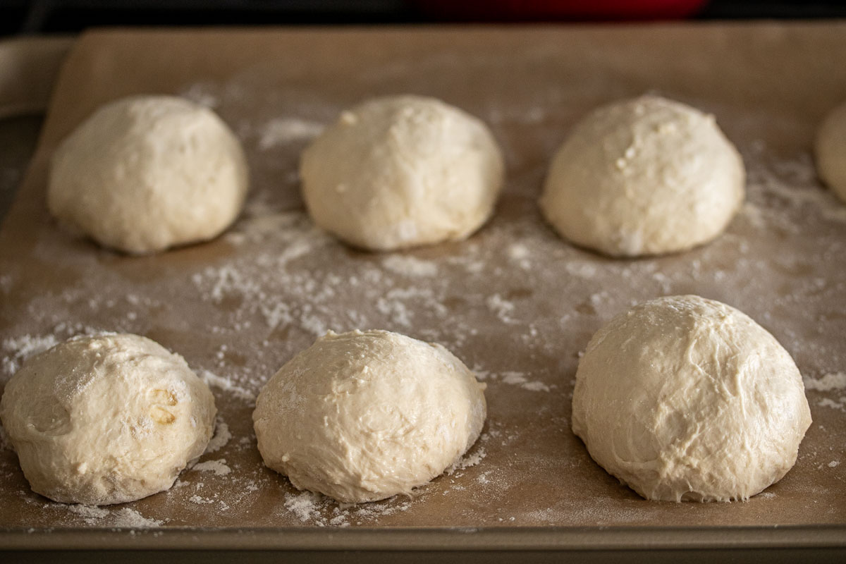 Rolls resting into lined and floured baking sheet.