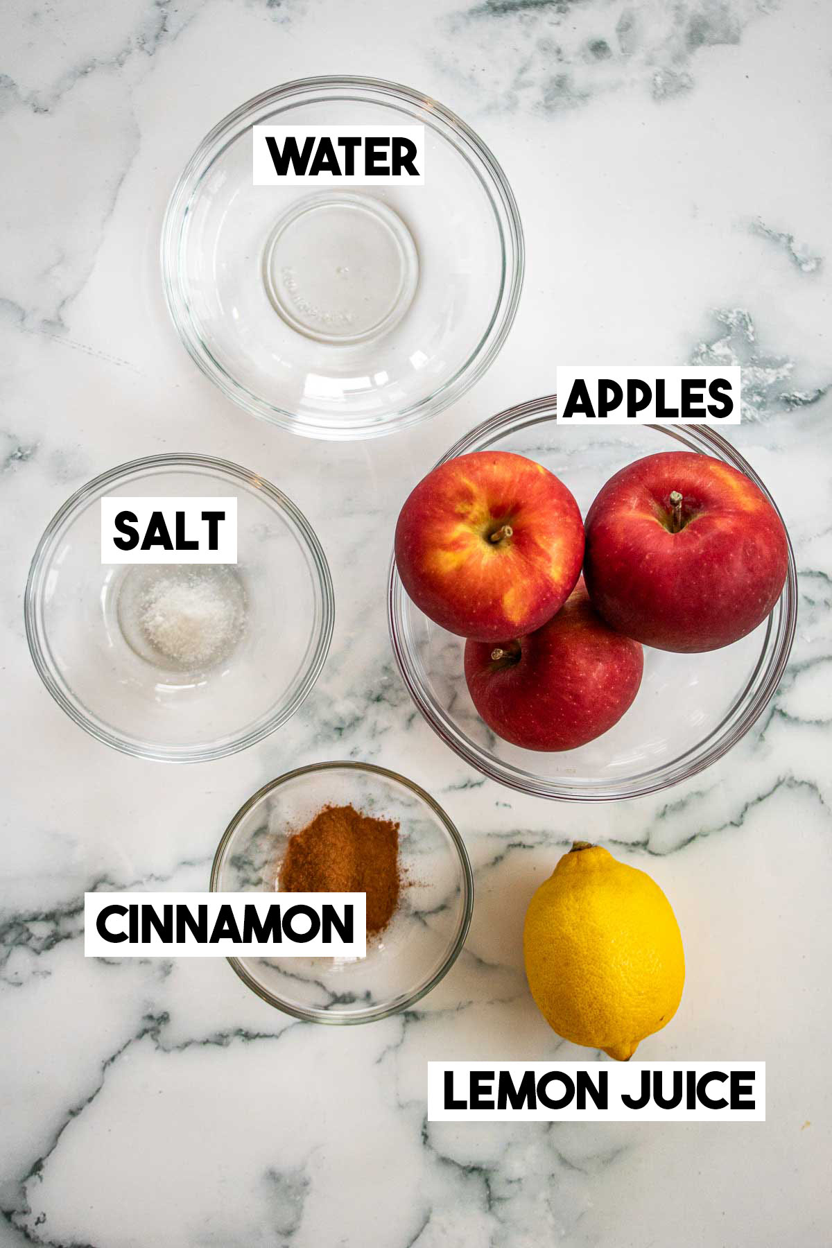 Ingredients of this recipe in bowls: apples, salt, water, lemon and cinnamon.