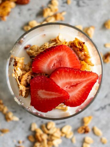 Sliced strawberries, granola and milk in a glass.