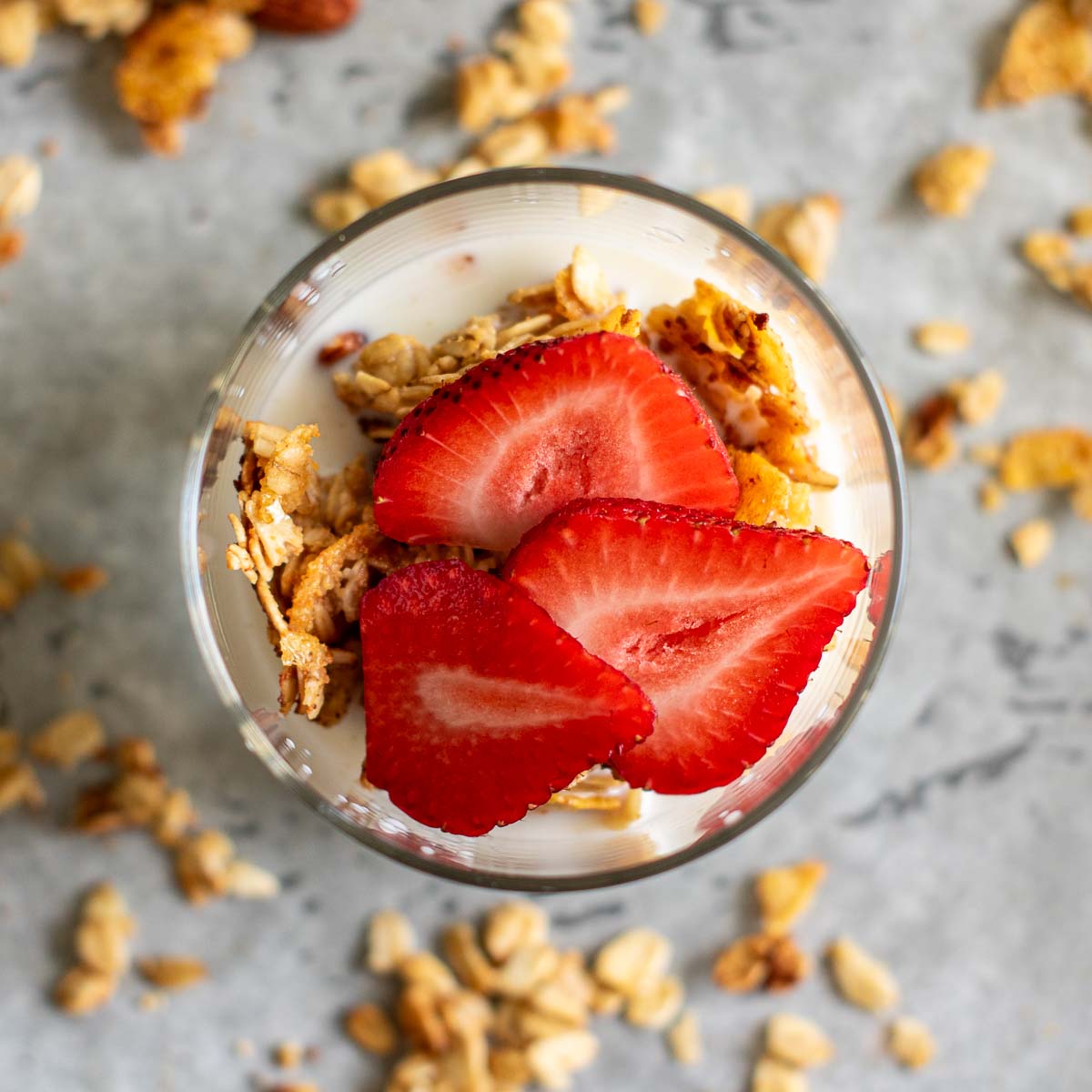 Sliced strawberries, granola and milk in a glass.