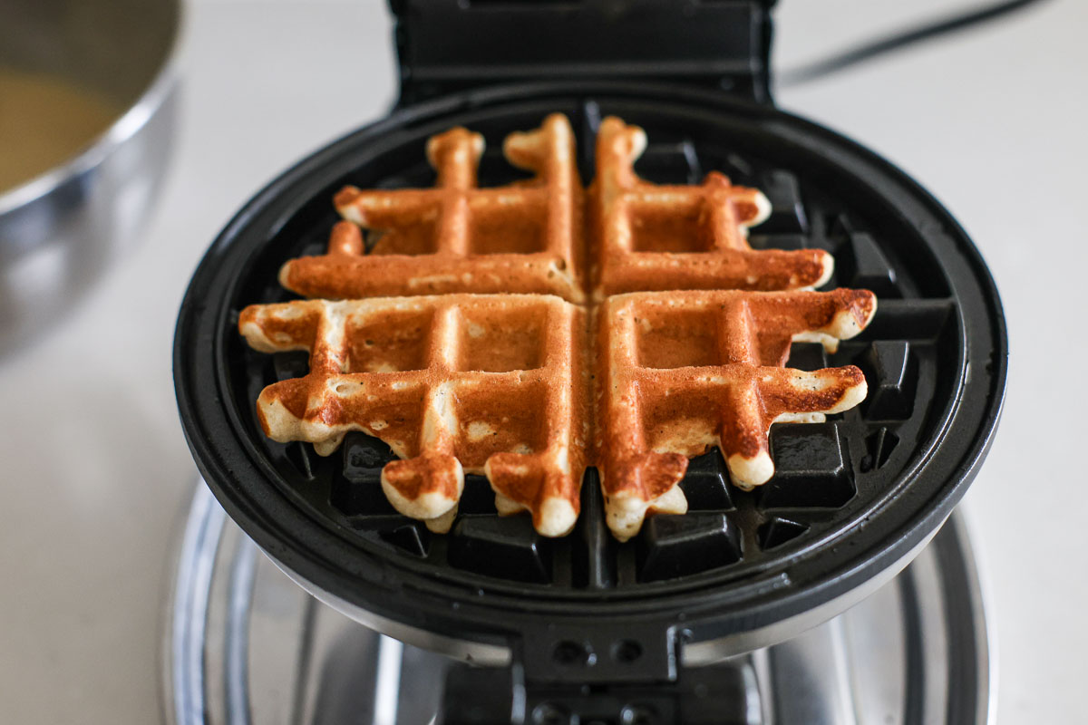 Golden brown Earl Grey waffle disk ready, in a waffle iron.