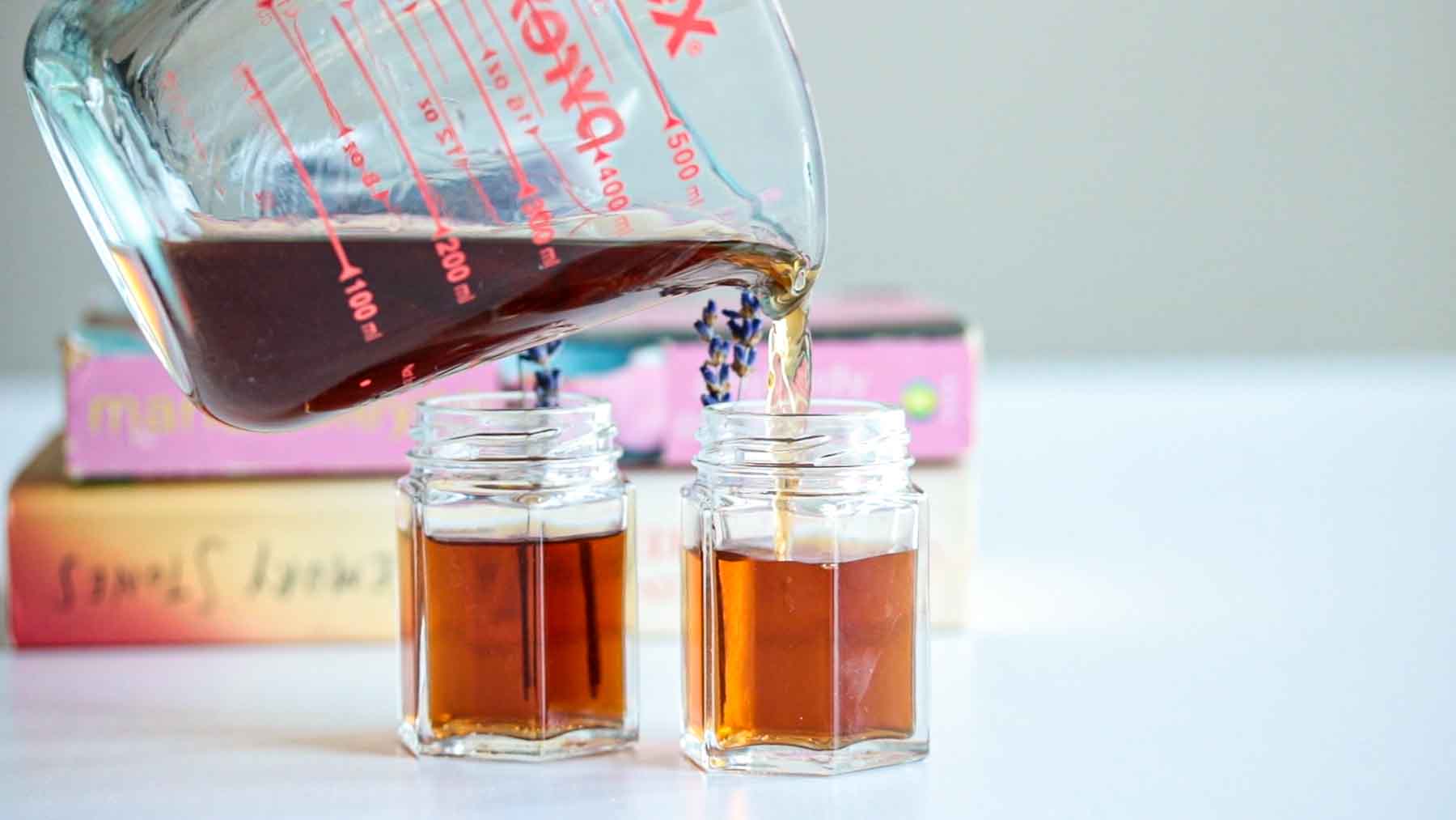 Lavender extract pouring into a glass jar.