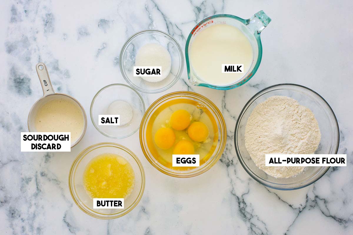 Ingredients separated into bowls: sourdough discard, salt, eggs, butter, milk, sugar and flour.