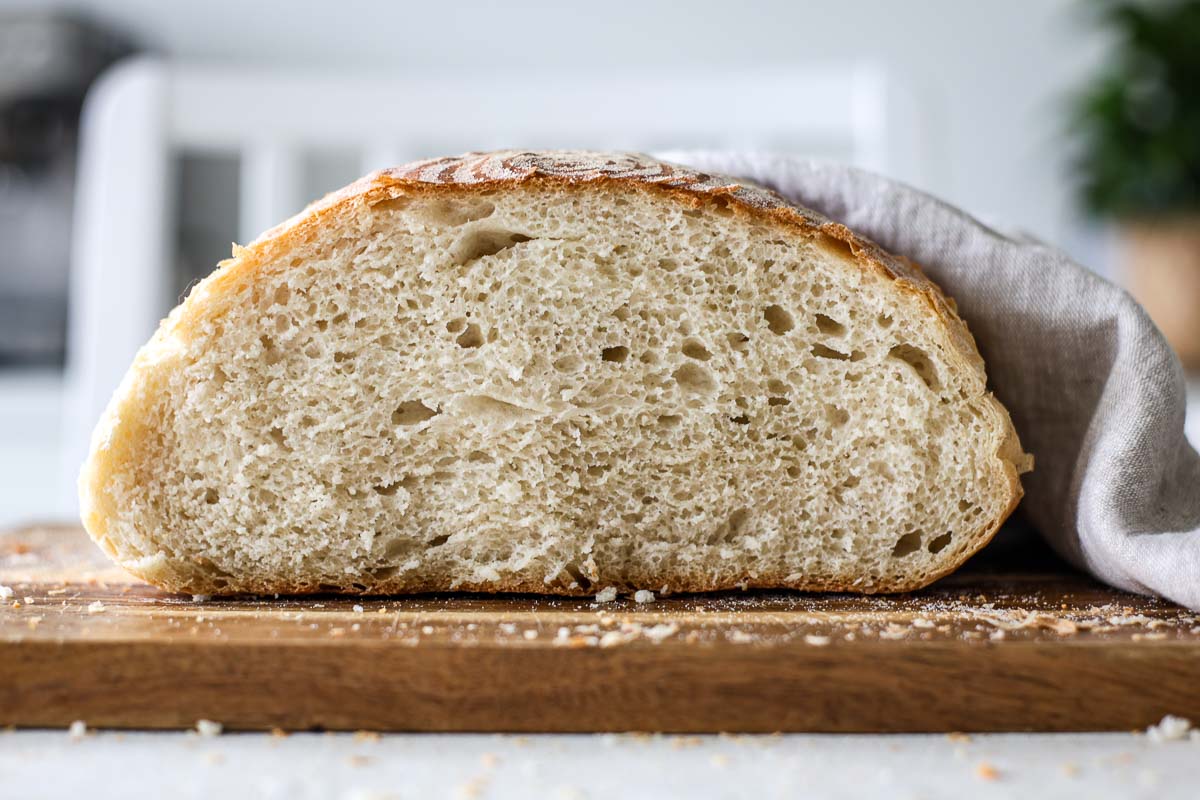 Sourdough discard bread sliced, showing its crumb, over a wooden board.