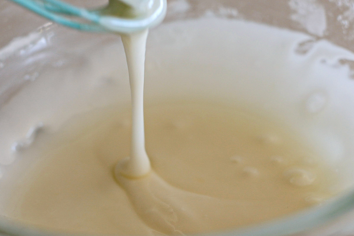 Lemon glaze dripping from a whisk.