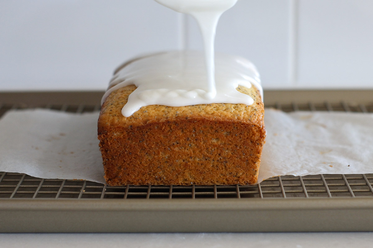 Drizzling glaze over baked lemon pound cake.