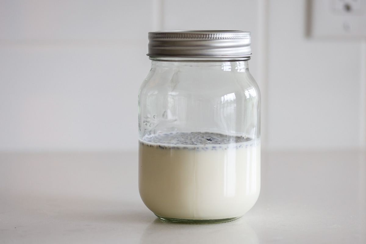 A glass jar with heavy cream and lavender, lid on.