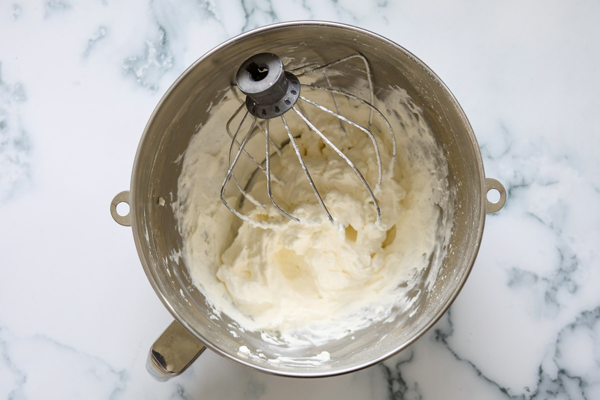 Lavender whippeed cream, whisk attachment, in a metal bowl.