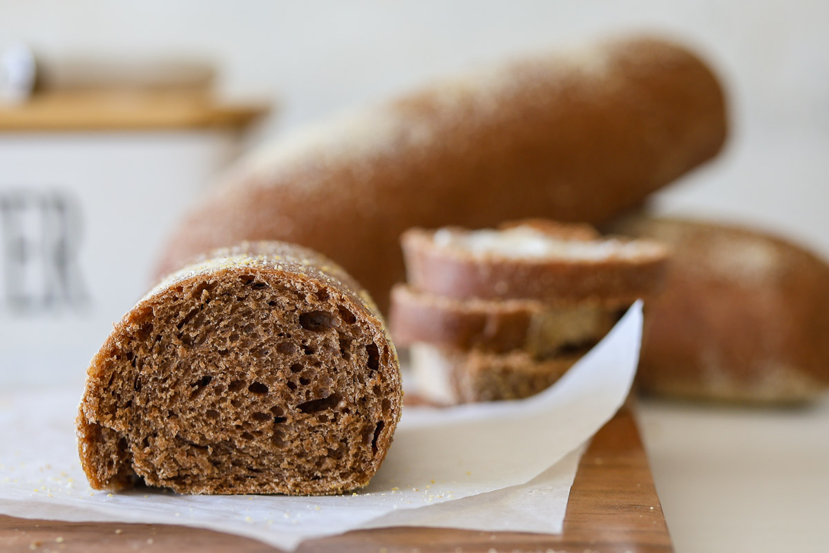 The crumb of a sourdough brown bread roll over a wooden board and parchment paper.