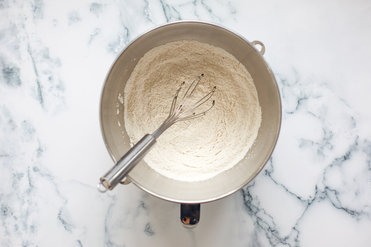 Dry ingredients with whisk inside metal bowl.