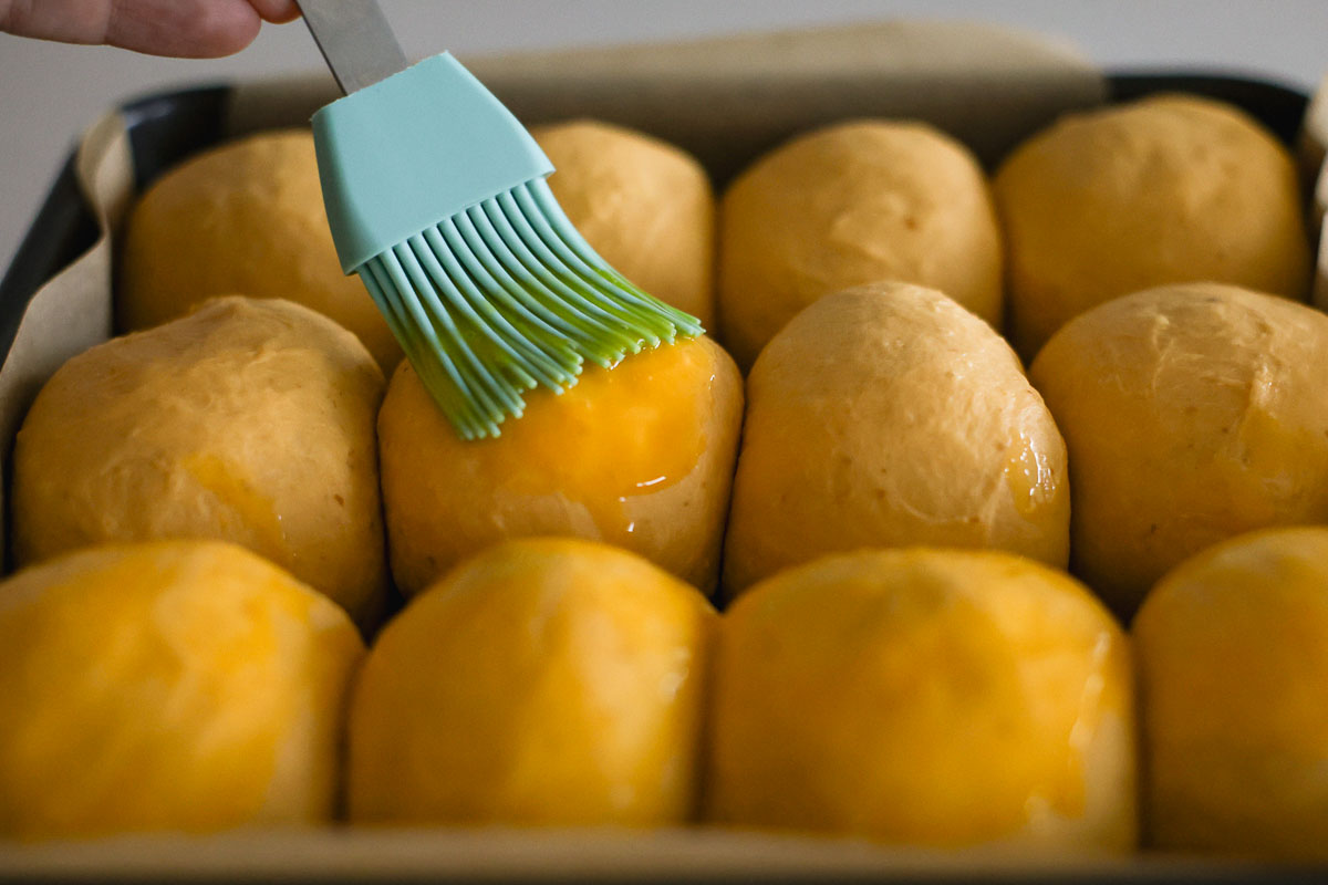 Hand brushing egg wash on top of dough.