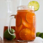 Thai Tea lemonade in a mug with lime slices and ice.