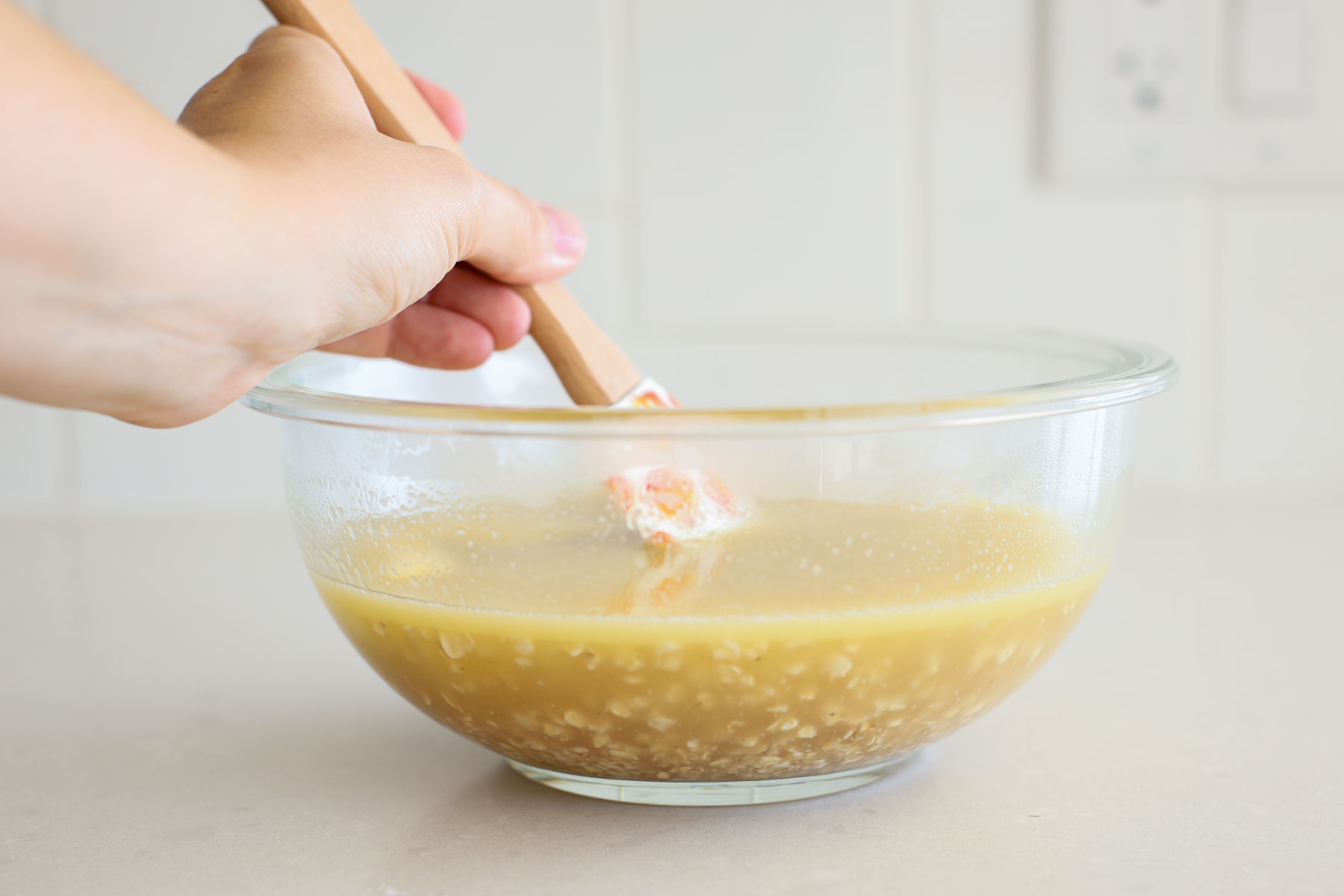 Oats, honey and butter soaked in water inside a transparent glass bowl.