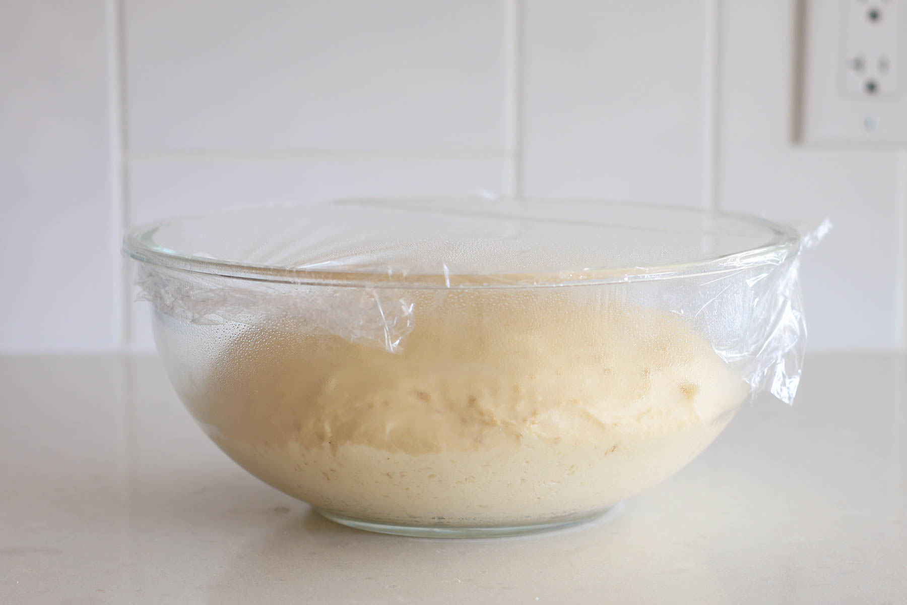 Risen dough inside glass bowl, covered.