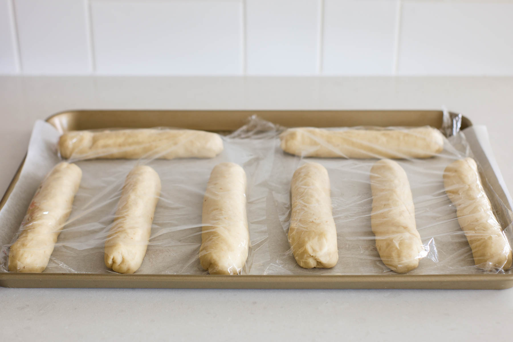 Shaped rolls covered into a baking sheet lined with parchment paper.