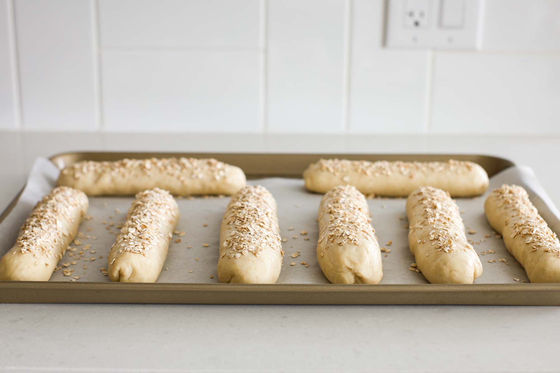 Rolls after the egg wash topped with quick oats.