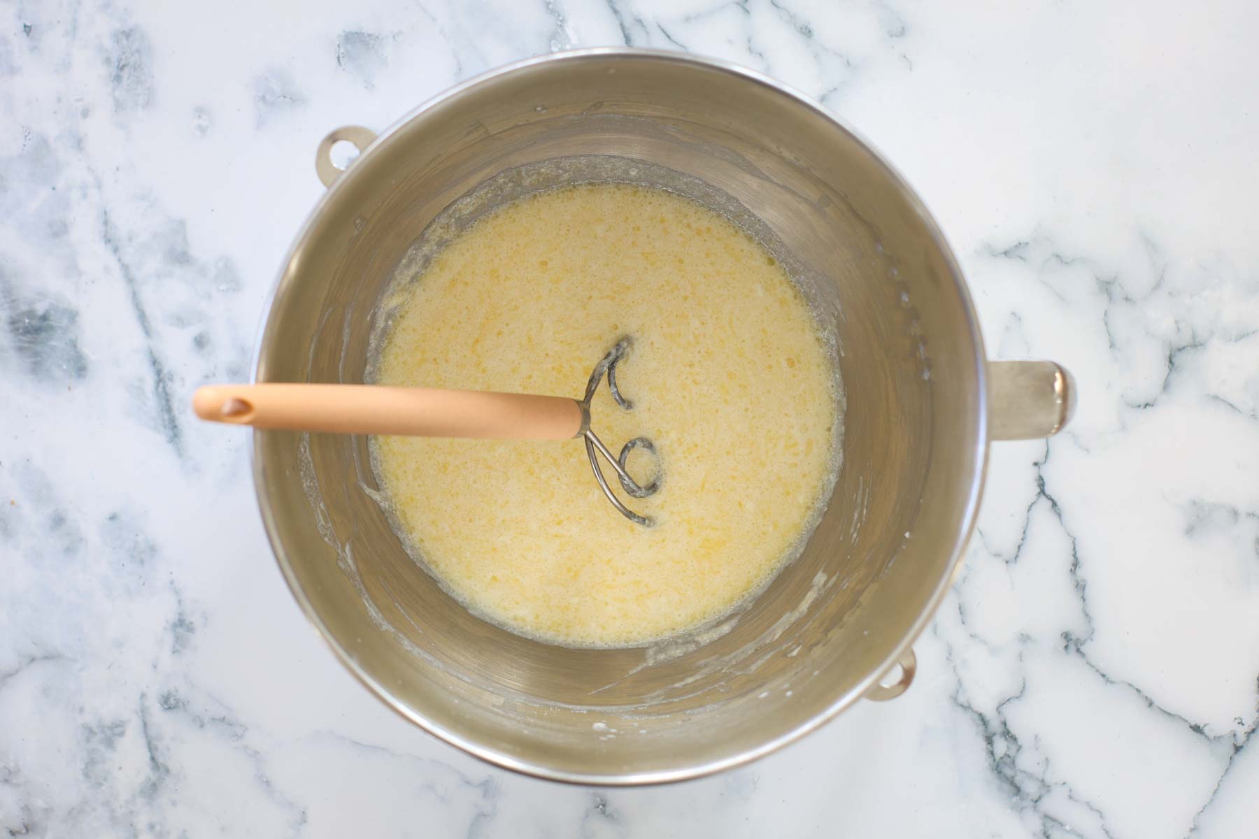 Wet ingredients in a metal bowl with a dough mixer.