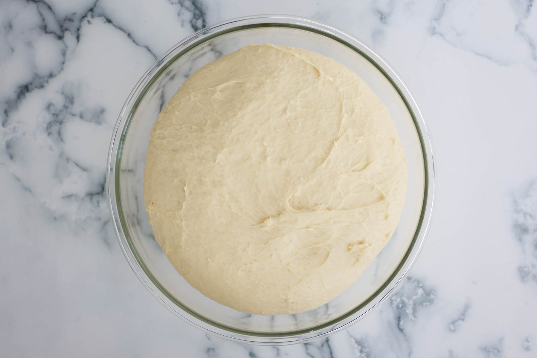 The dough in a glass bowl, after the first rise.