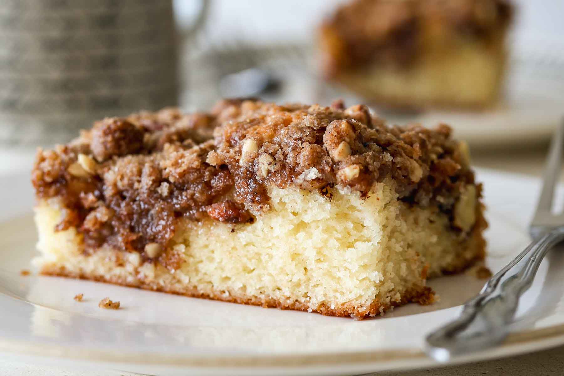 Sourdough apple coffee cake with a streusel topping on a white plate with a fork on the side.