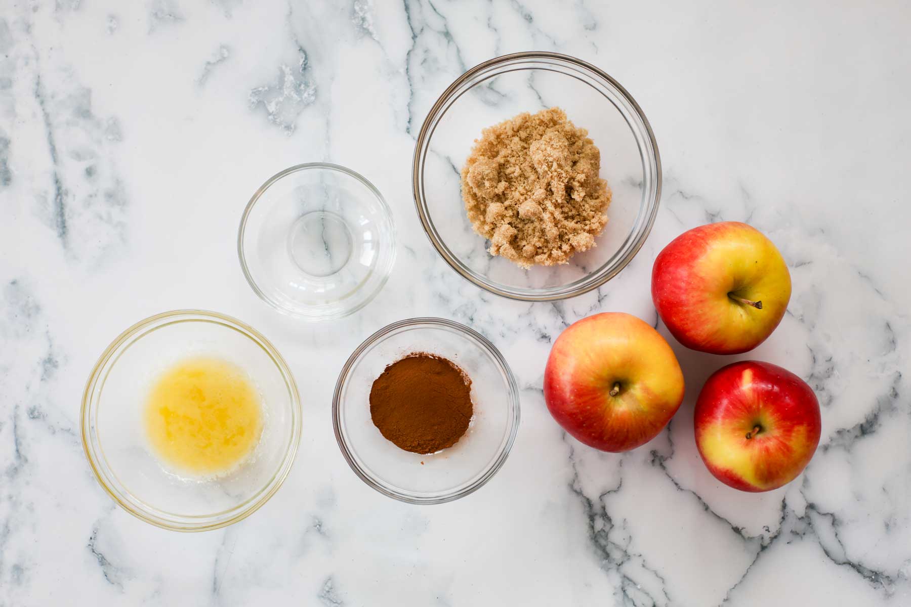 Apples and cinnamon, brown sugar, vinegar plus melted butter in bowls.