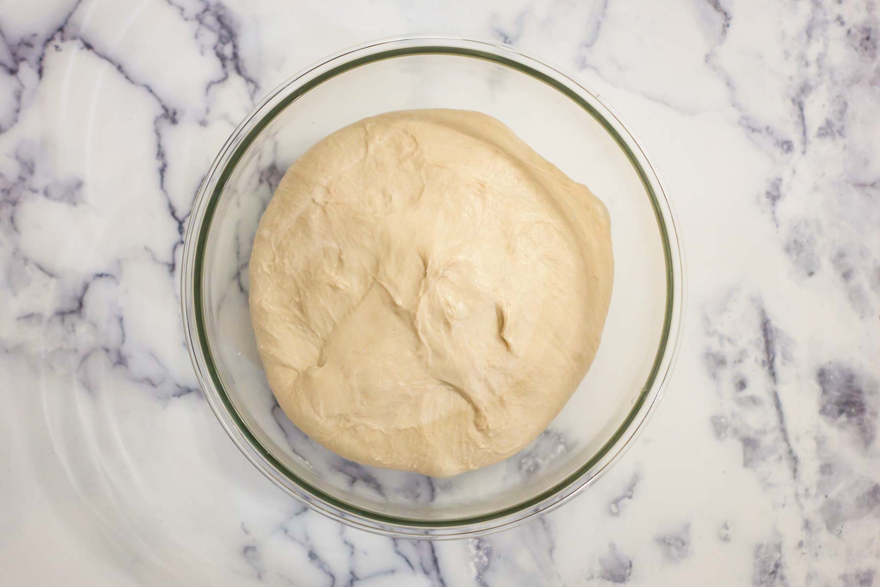 Dough after bulk fermentation in a glass bowl.