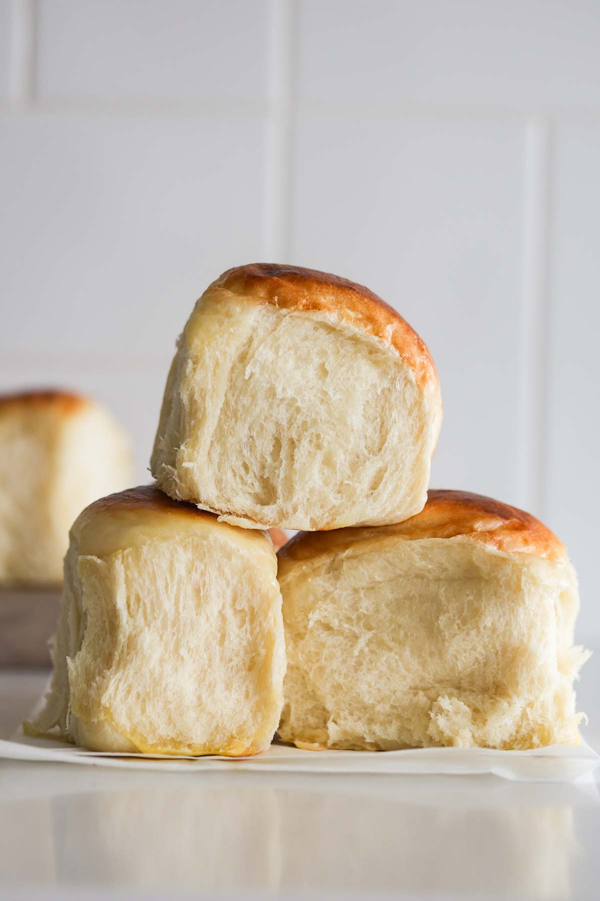 Three sourdough Hawaiian rolls on top of parchment paper.