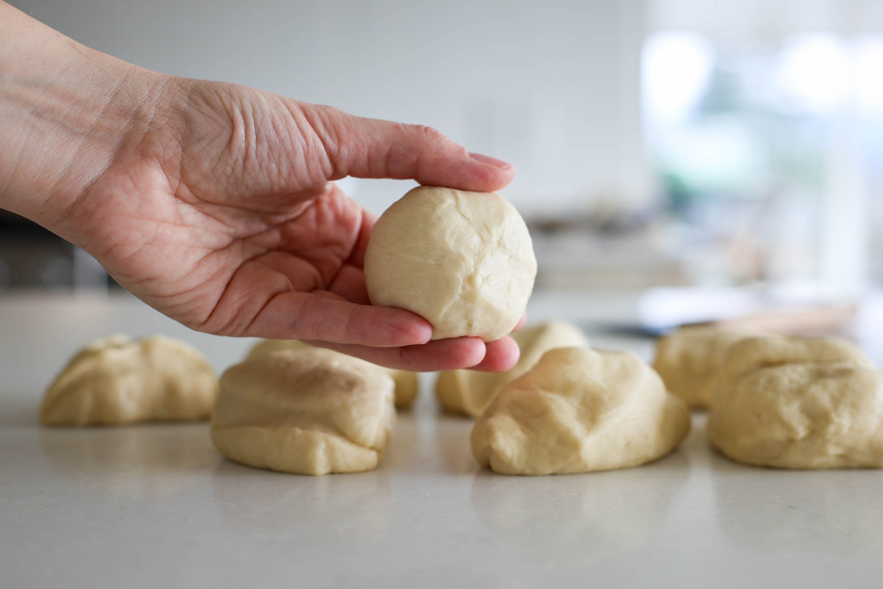 A hand holding a ball shaped dough.