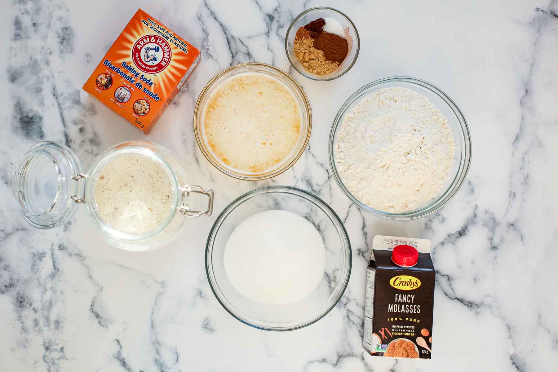 Ingredients for sourdough gingerbread cookies on a marble table.
