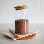Chocolate sourdough starter in a jar with spoon.